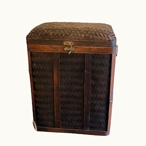 May include: A square, woven bamboo storage chest with a hinged lid and a metal clasp. The chest is primarily dark brown with lighter brown accents and vertical bamboo strips. The lid and sides feature a woven pattern.