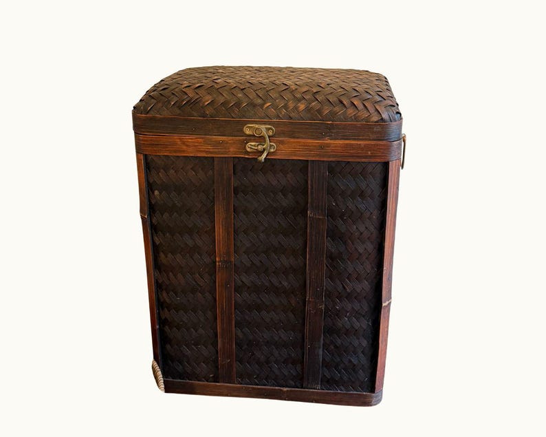 May include: A square, woven bamboo storage chest with a hinged lid and a metal clasp. The chest is primarily dark brown with lighter brown accents and vertical bamboo strips. The lid and sides feature a woven pattern.