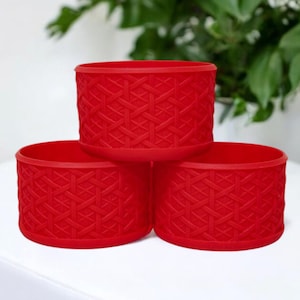 May include: Three red cylindrical containers with a woven pattern. The containers are stacked on top of each other.