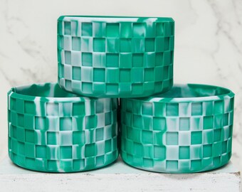 Puede incluir: Tres cuencos de silicona verde y blanco a cuadros apilados uno encima del otro. Los cuencos tienen un efecto marmoleado.