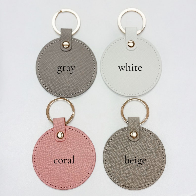 Pu&ograve; includere: Quattro portachiavi rotondi in grigio, bianco, corallo e beige. Ogni portachiavi ha un anello color oro e un cinturino abbinato con un bottone a pressione dorato. I colori sono etichettati su ogni portachiavi.