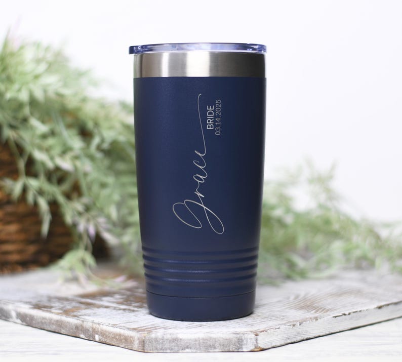 May include: A navy blue stainless steel tumbler with a white inscription that reads "Grace Bride 03.14.2025".