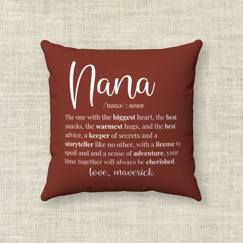 May include: Red throw pillow with white text defining "Nana" as "The one with the biggest heart, the best snacks, the warmest hugs, and the best advice, a keeper of secrets and a storyteller like no other, with a license to spoil and a sense of adventure, your time together will always be cherished. love, maverick"
