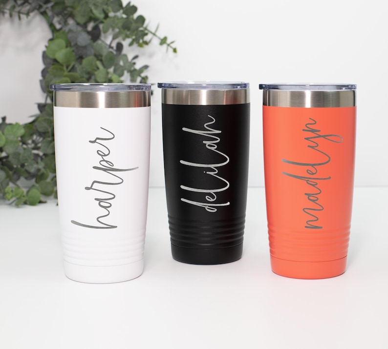May include: Three stainless steel tumblers with personalized names: Harper, Delilah, and Madelyn. The tumblers are white, black, and orange.