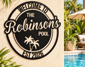 May include: A circular black metal wall sign featuring the text "WELCOME TO THE Robinson's POOL" and "EST 2026" with a cutout graphic of two palm trees. The sign has a bold, clean design with cut-out lettering and a circular frame border.
