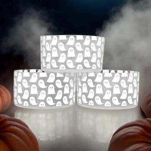 May include: Three white ceramic bowls with a ghost pattern. The bowls are stacked on top of each other.