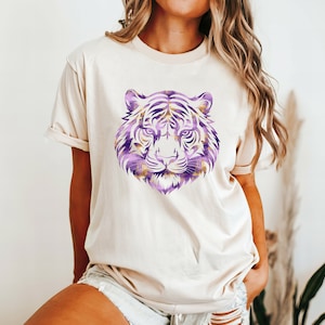 May include: A white t-shirt featuring a purple and gold tiger face graphic.