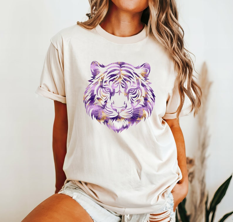 May include: A white t-shirt featuring a purple and gold tiger face graphic.