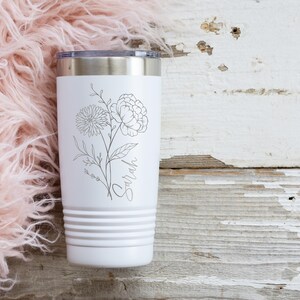 May include: White stainless steel tumbler with a floral design and the name "Sarah" printed on it.