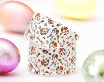May include: Two white ceramic Easter egg cups with a pattern of bunnies, eggs, and carrots. The cups are stacked on top of each other.