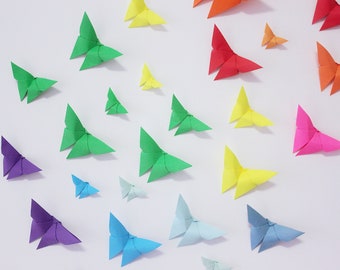 May include: A white wall decorated with colourful origami butterflies in various shades of blue, green, yellow, red, and purple.