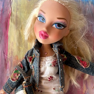 Blonde hair Bratz Cloe doll wearing a denim jacket over an embroidered floral dress and a matching handbag