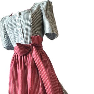 Puede incluir: Vestido tradicional con corpiño de cuadros verdes y blancos y mangas cortas. La falda es roja con rayas blancas y un lazo a juego en la cintura. El vestido es de estilo clásico, adecuado para diversas ocasiones.