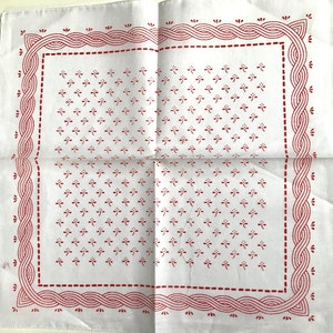 May include: White cotton handkerchief with a red embroidered border and a repeating pattern of small red flowers inside the border.