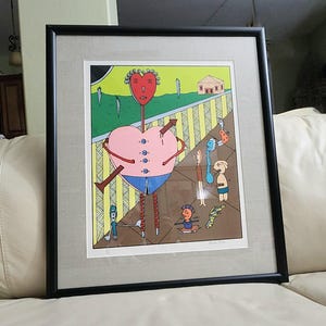 May include: Framed art print featuring a whimsical illustration of a heart-shaped figure with an arrow through it, wearing blue shorts and connected to a chain. The artwork has a black frame and a light gray mat.