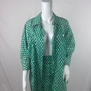 Op de afbeelding: Een groene en witte geometrische geprinte shirt en rok set. Het shirt heeft een kraag en knoopsluiting. De rok is A-lijn en valt tot op de knieën.