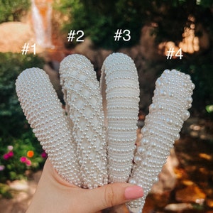May include: Four white pearl headbands, labeled #1, #2, #3, and #4. The headbands are made of small white pearls and are arranged in a hand.