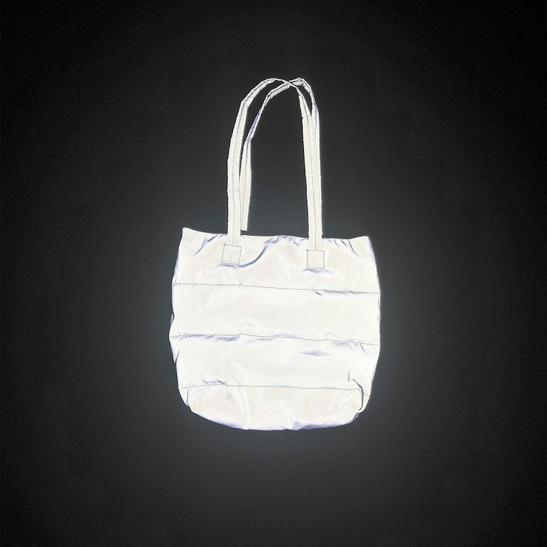 May include: A silver reflective tote bag with two handles. The bag has a quilted design.