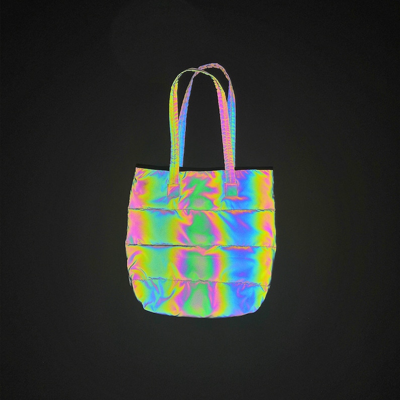May include: A iridescent, quilted tote bag with a rainbow sheen. The bag has two straps and a rectangular shape.