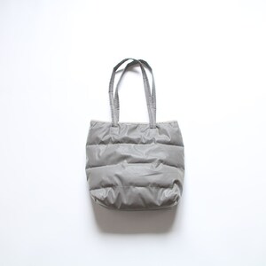 May include: A gray quilted tote bag with two handles.
