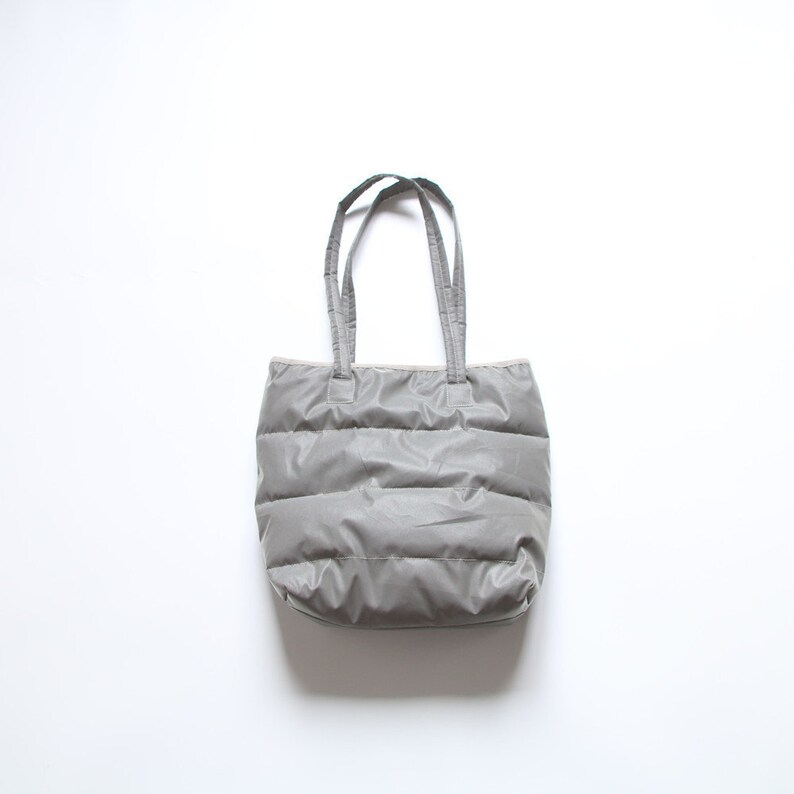 May include: A gray quilted tote bag with two handles.