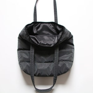May include: A black quilted tote bag with two shoulder straps. The bag is empty and the inside is visible.