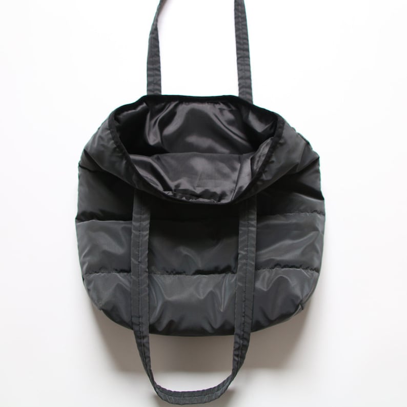 May include: A black quilted tote bag with two shoulder straps. The bag is empty and the inside is visible.