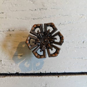 Op de afbeelding: Een sierlijke, bloemvormige ladegreep in brons met een gedetailleerd centraal ontwerp.