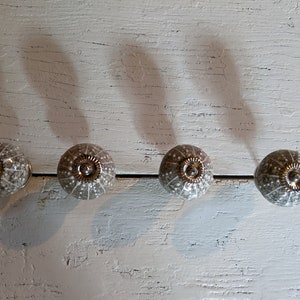 May include: Four ceramic cabinet knobs in a light gray color with a white speckled pattern. Each knob has a silver metal center.