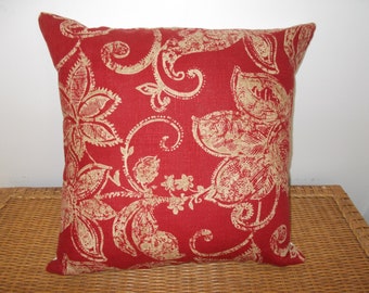 May include: Red throw pillow with a gold floral pattern. The pillow is made of a soft, textured fabric.