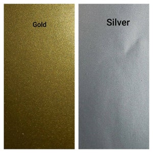 May include: Two swatches of metallic paint, one gold and one silver. The swatches are side-by-side and show the texture of the paint.
