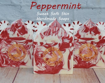 May include: Handmade peppermint soaps with red and white swirls, topped with peppermint candy decorations. The soaps have a gold emblem and the text "Peppermint Sweet Soft Skin Handmade Soaps" is visible.