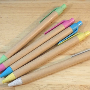Op de afbeelding: Vijf bruine kartonnen pennen met verschillende gekleurde punten. De punten zijn groen, roze, blauw, geel en wit.