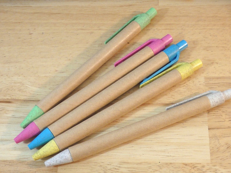 Op de afbeelding: Vijf bruine kartonnen pennen met verschillende gekleurde punten. De punten zijn groen, roze, blauw, geel en wit.