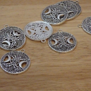 May include: A set of silver-toned metal charms featuring a triple moon and pentacle design. The charms are round and have intricate details.