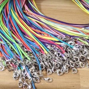 May include: A large assortment of colorful cords with silver clasps. The cords are arranged in a pile and are all different colors, including red, blue, green, yellow, and purple.