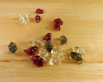 May include: An assortment of heart-shaped charms in various colours, including red, clear, and grey. The charms are made of glass and have a gold-coloured loop for attaching to jewellery or other crafts.