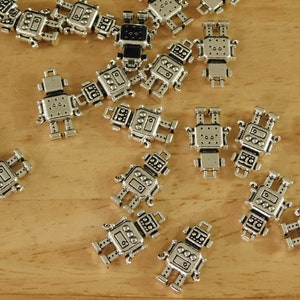 May include: A collection of silver robot charms, each with a unique design. The charms are small and detailed, with a metallic finish. They are perfect for adding a whimsical touch to jewelry or crafts.