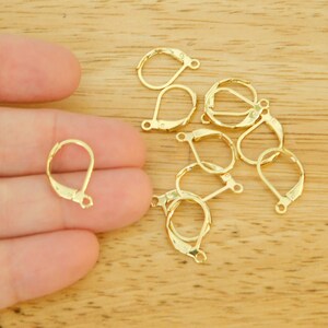 May include: A close-up of ten gold-toned earring hooks. The hooks are made of metal and have a teardrop shape. They are designed to be used with a variety of earring styles.