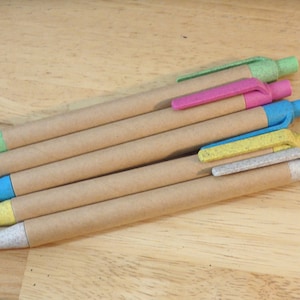 Op de afbeelding: Vijf bruine kartonnen pennen met verschillende gekleurde dopjes. De dopjes zijn groen, roze, blauw, geel en wit.