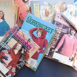 May include: A stack of vintage Workbasket magazines featuring various knitting and crocheting patterns. The covers feature women wearing colorful knitted garments and the magazine titles are visible.