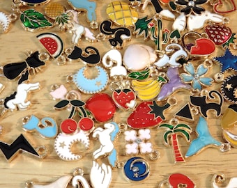 May include: Assortment of colorful enamel charms with gold-tone metal loops. Charms include a variety of shapes and designs, such as a crescent moon, a cat, a strawberry, a pineapple, a palm tree, a unicorn, a cherry, and a star.