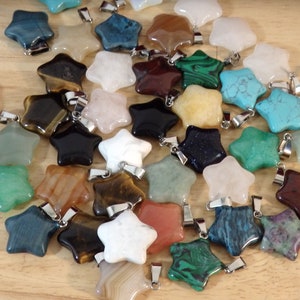 May include: A collection of star-shaped pendants made from various types of polished stones, including tiger's eye, agate, turquoise, and malachite. Each pendant has a silver-toned bail.