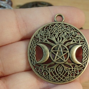 May include: A bronze pendant featuring a Celtic knot design with a triple moon and pentagram symbol. The pendant is circular and has a loop at the top for hanging.