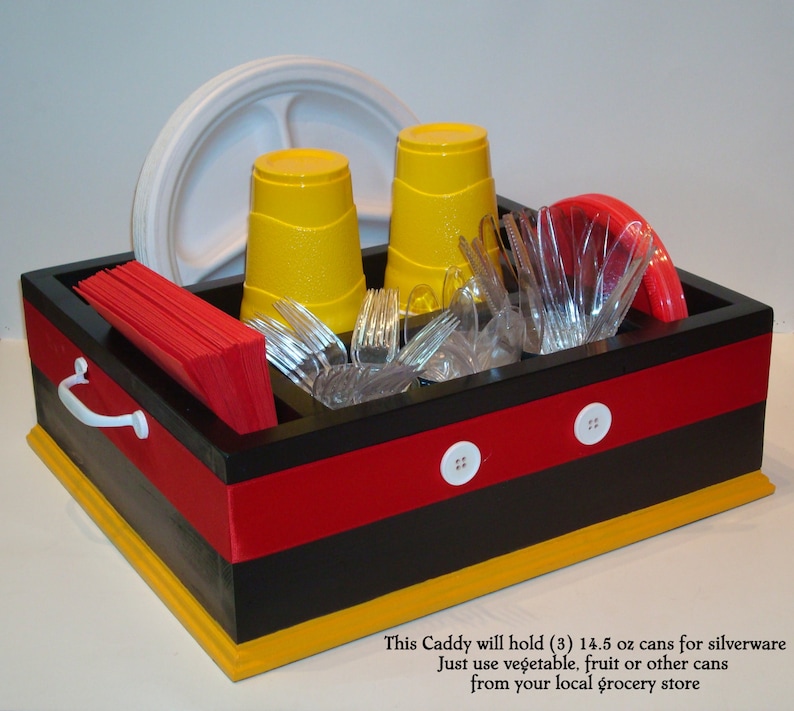 Puede incluir: Un organizador negro, rojo y amarillo con botones blancos y un asa. Contiene vasos amarillos, cubiertos de pl&aacute;stico transparente, servilletas rojas y un plato blanco. El organizador est&aacute; dise&ntilde;ado para cubiertos y utiliza latas de la tienda.