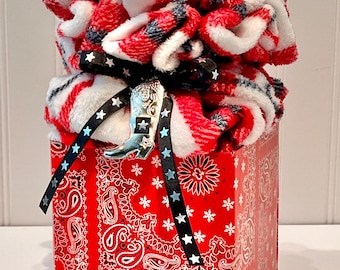 Esta suave manta en una elegante caja estilo western es un regalo perfecto para cualquier ocasión; manta a cuadros negros, blancos y rojos en una caja de regalo.