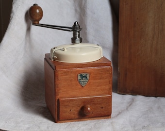 Antique french wooden coffee grinder with cream color metal top. French country kitchen. Rustic farmhouse decor. Manual coffee grinder