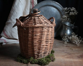 French vintage demi-john wine bottle in wicker basket. Rustic French farmhouse. Wine jug basket. French country kitchen.