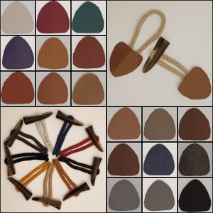 Könnte beinhalten: Sortiment von 12 Lederknöpfen in verschiedenen Farben und Texturen, darunter Braun, Rot, Grün, Blau und Grau. Die Knöpfe werden mit einem Satz von 12 passenden Hornknöpfen und Schnüren gezeigt.