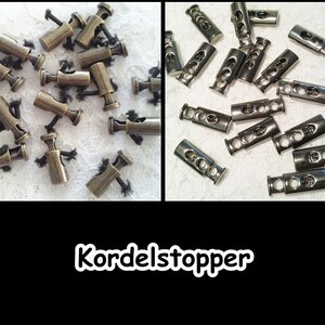 Könnte beinhalten: Zwei Sätze Metall-Kordelstopper. Der erste Satz ist in Antikgold und der zweite in Silber. Beide Sätze werden zum Sichern von Kordeln oder Kordeln verwendet.